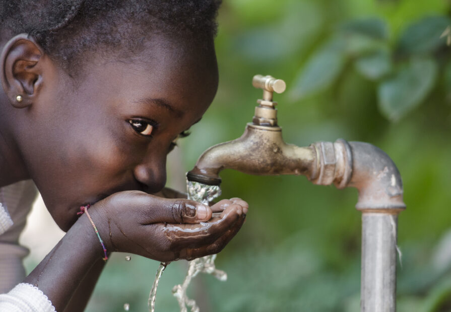 Kind trinkt von öffentlichem Wasserhahn